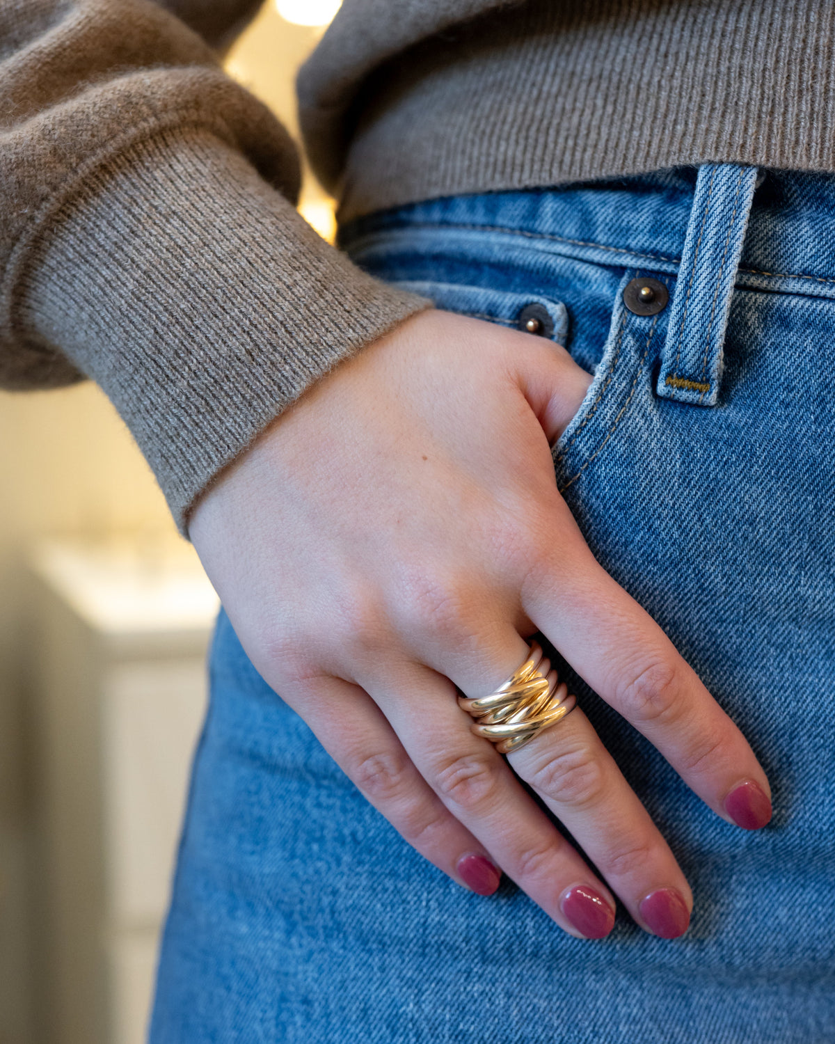 14K gold-filled Double Crossover Band worn on a hand beside blue jeans.
