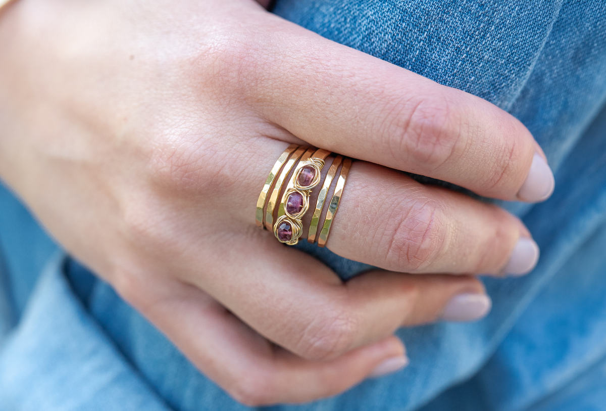 Mila Nest Ring with tourmaline stones and gold bands on a hand over denim